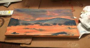 A painting of the sky and clouds on top of cardboard.