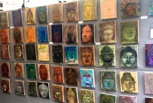 A wall of paintings with faces painted on them.