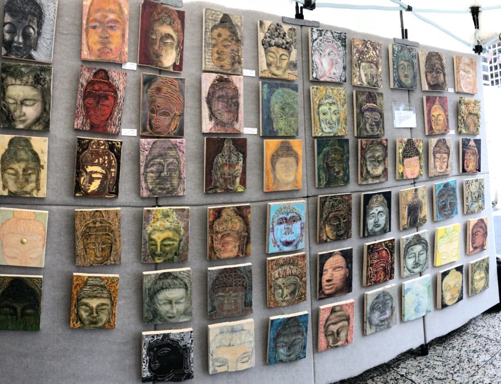 A wall of faces on display at an art show.