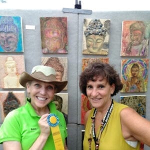 A woman holding a ribbon in front of many paintings.