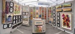 Art exhibit booth with colorful framed paintings.