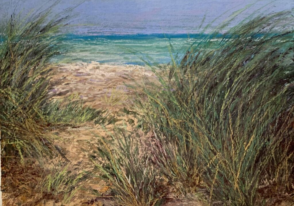 Beach dunes with grass and ocean view.