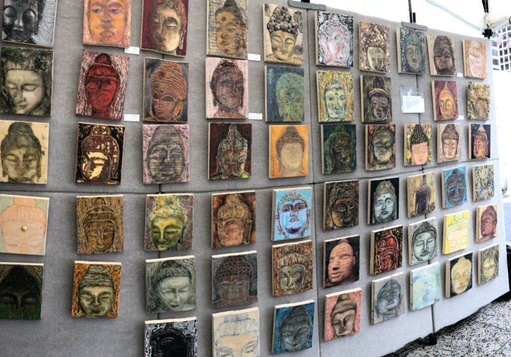 Wall displaying colorful Buddha face artwork panels.