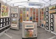 Art exhibit booth with colorful framed paintings.